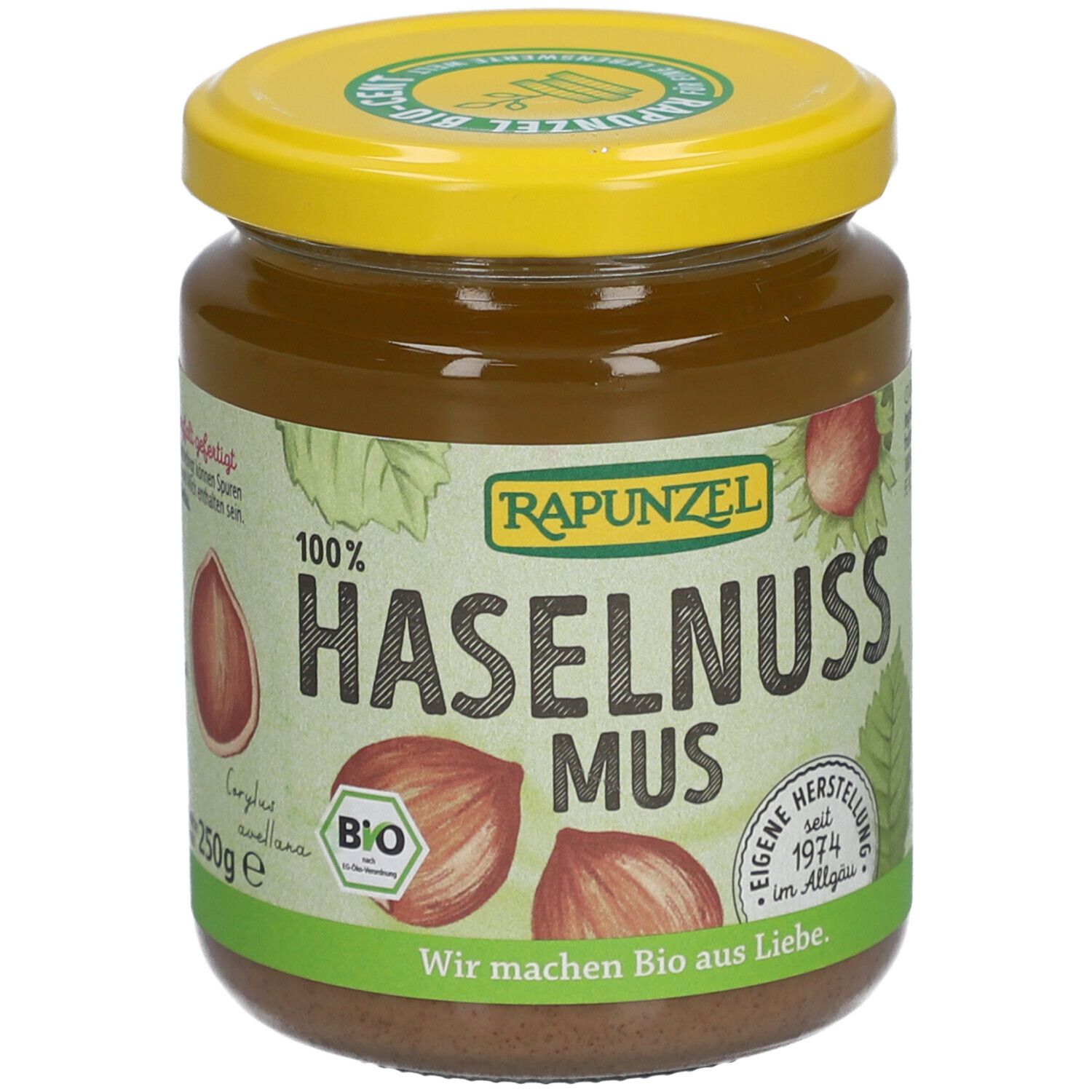 Glas mit Haselnussmus. Gelber Deckel, Etikett mit Text und Haselnuss-Illustrationen. Aufschrift: RAPUNZEL, BIO, 250g.