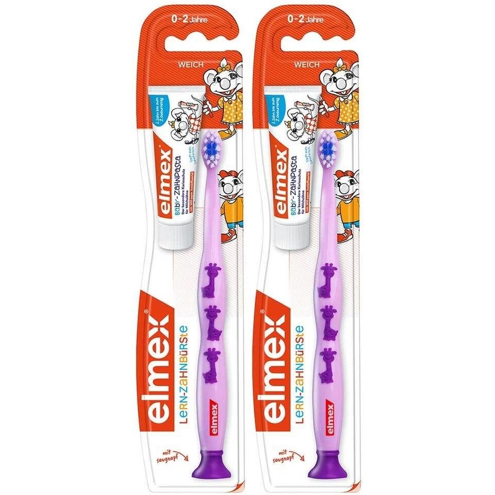 Zwei Kinderzahnbürsten in Verpackung. Lila Bürsten mit Giraffenmuster. Auf der Verpackung steht "elmex LERN-ZAHNBÜRSTE".