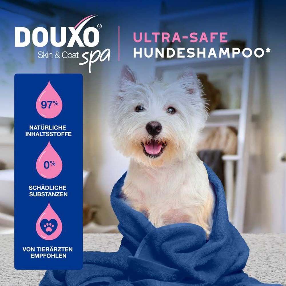 Chien blanc dans une serviette bleue. Texte : Shampooing DOUXO® SPA Ultra-safe pour chiens. 97% ingrédients naturels, 0% substances nocives.
