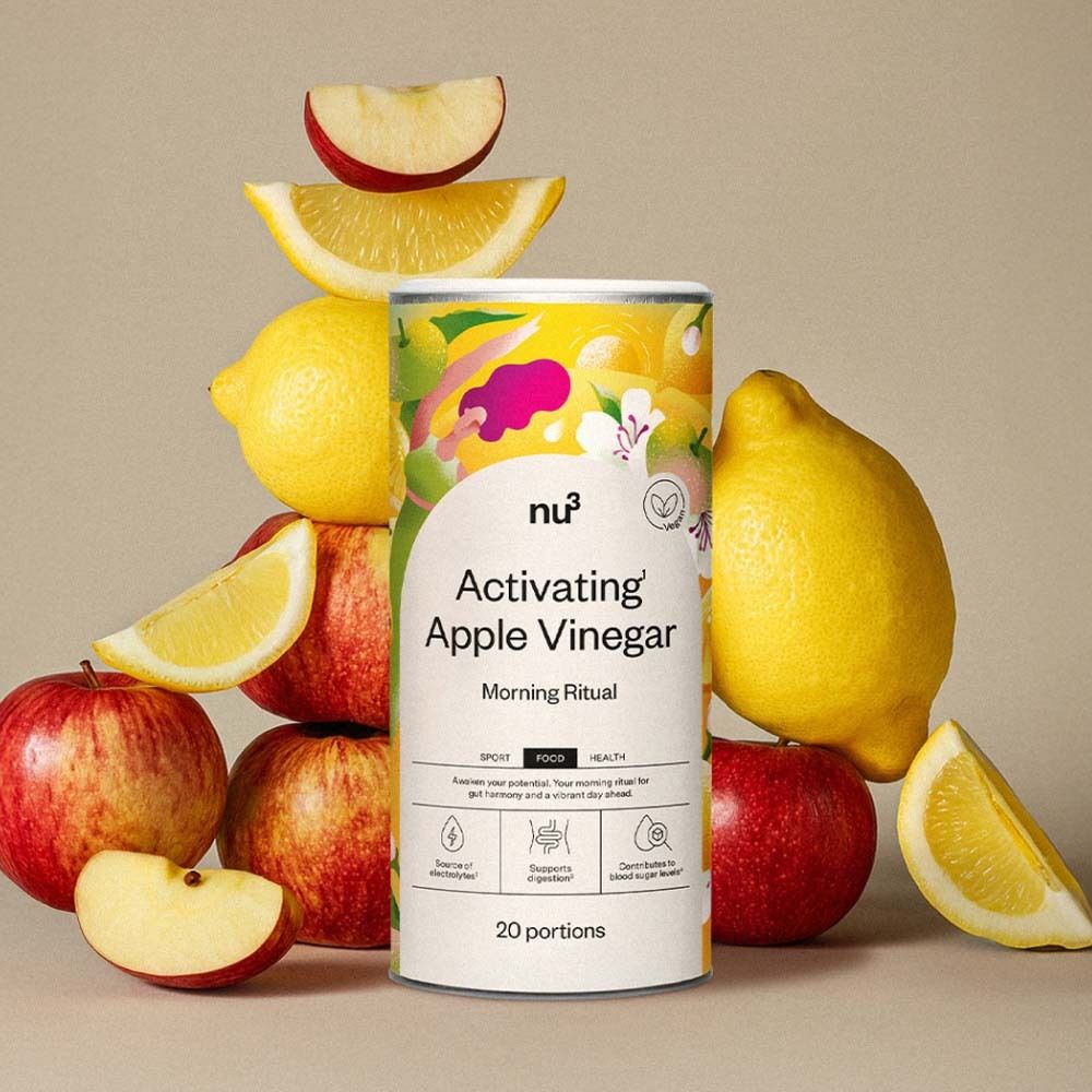 Boîte "nu3 Activating Apple Vinegar" entourée de pommes et citrons. Nom du produit et logo visibles. 20 portions.