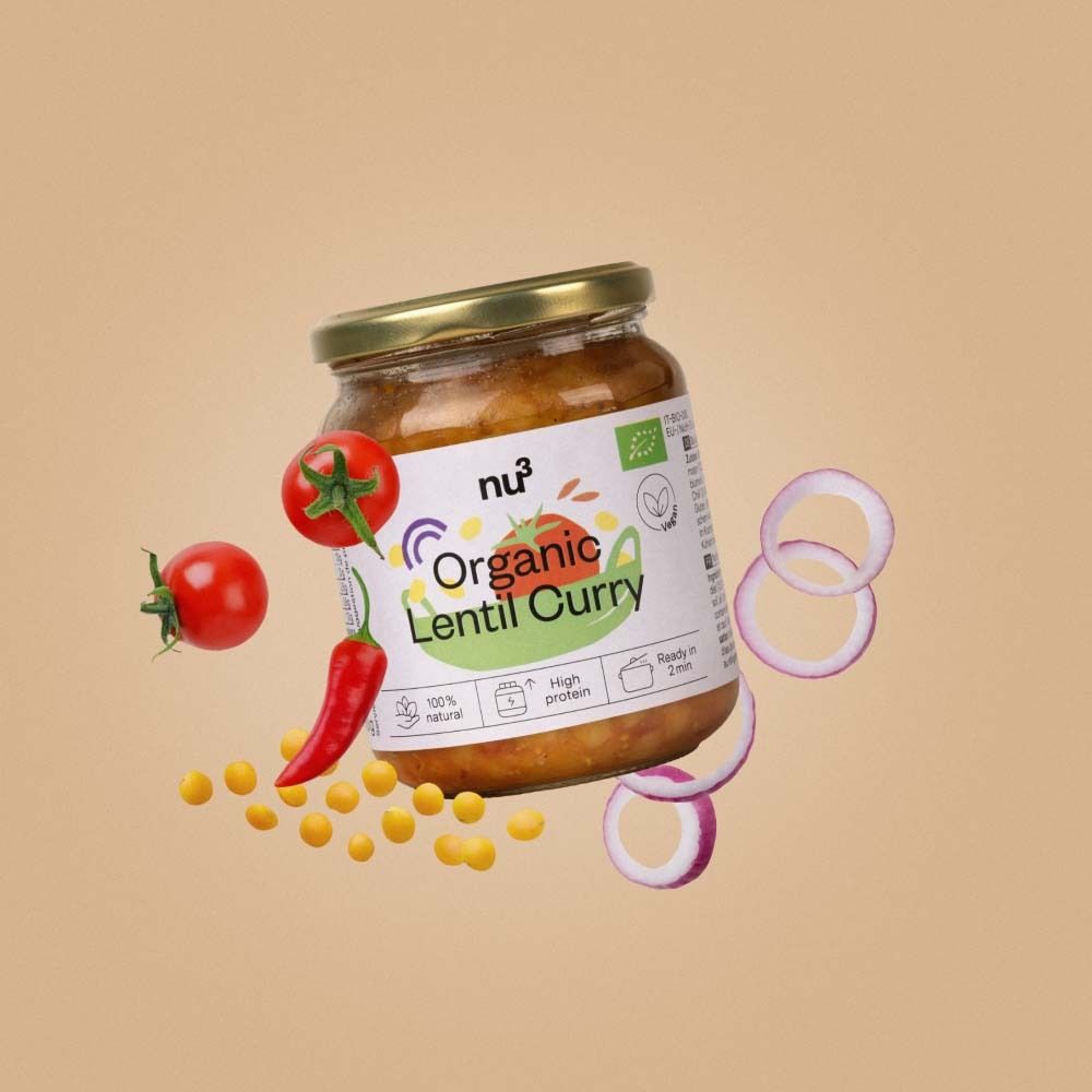 Glas mit nu3 Organic Linsen-Curry, umgeben von Tomaten, Chili und Zwiebelringen.