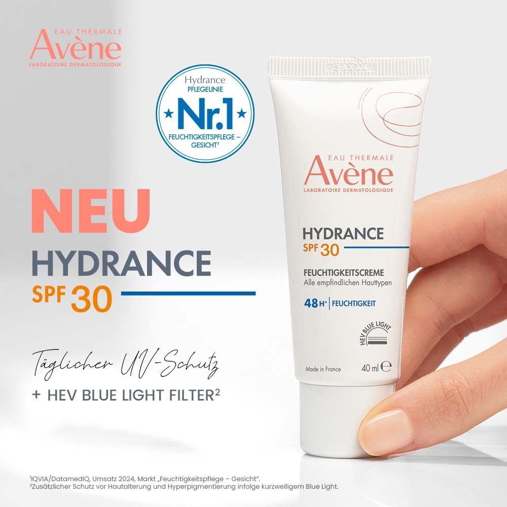 Main tenant Avène Hydrance crème hydratante SPF 30. Texte : Protection UV quotidienne + filtre lumière bleue HEV. Tube blanc, 40 ml.
