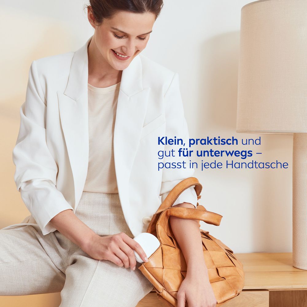 Une femme range le NIVEA CELLULAR Expert Finish 3in1 Pflege Cushion dans un sac à main.