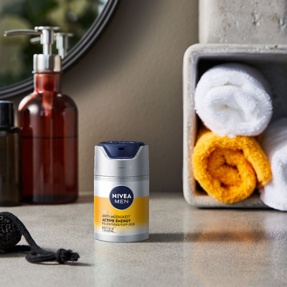 NIVEA MEN Active Energy Feuchtigkeitspflege auf einem Badezimmertisch mit Handtüchern.