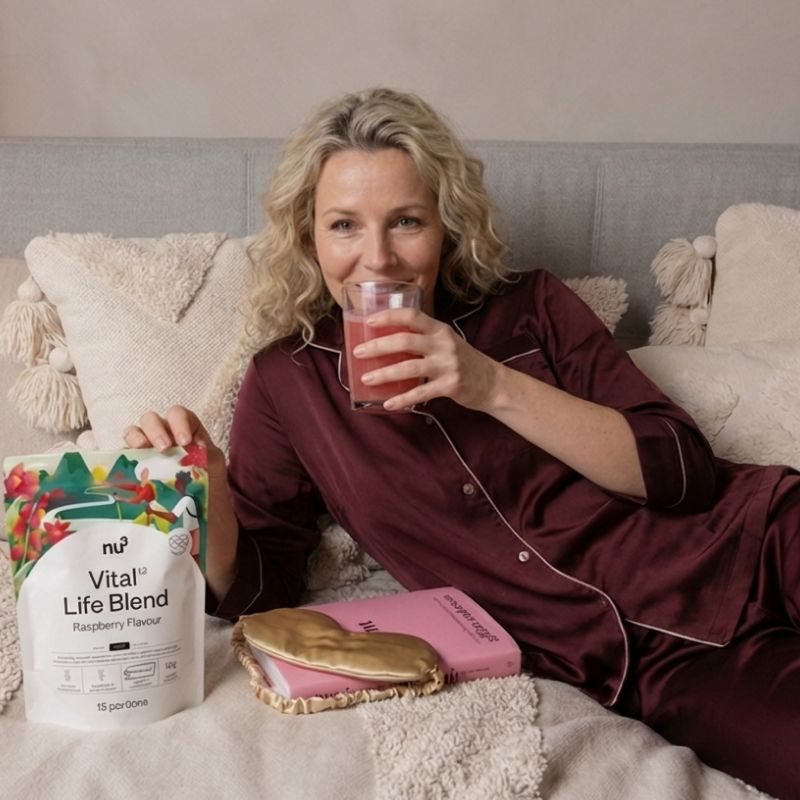Femme buvant nu3 Vital Life Blend saveur framboise au lit avec l'emballage.