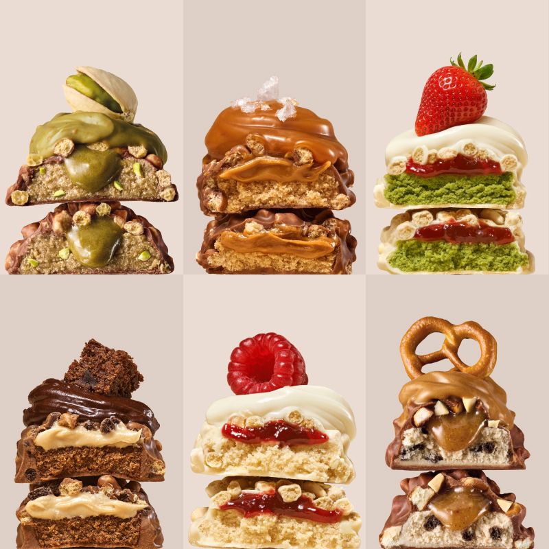 Six variantes de barres protéinées empilées, dont Fraise-Matcha avec une fraise fraîche.