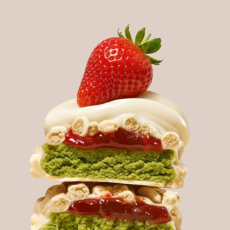 Vue détaillée d'une barre protéinée Fraise-Matcha enrobée de chocolat blanc, avec fraise et garniture matcha.