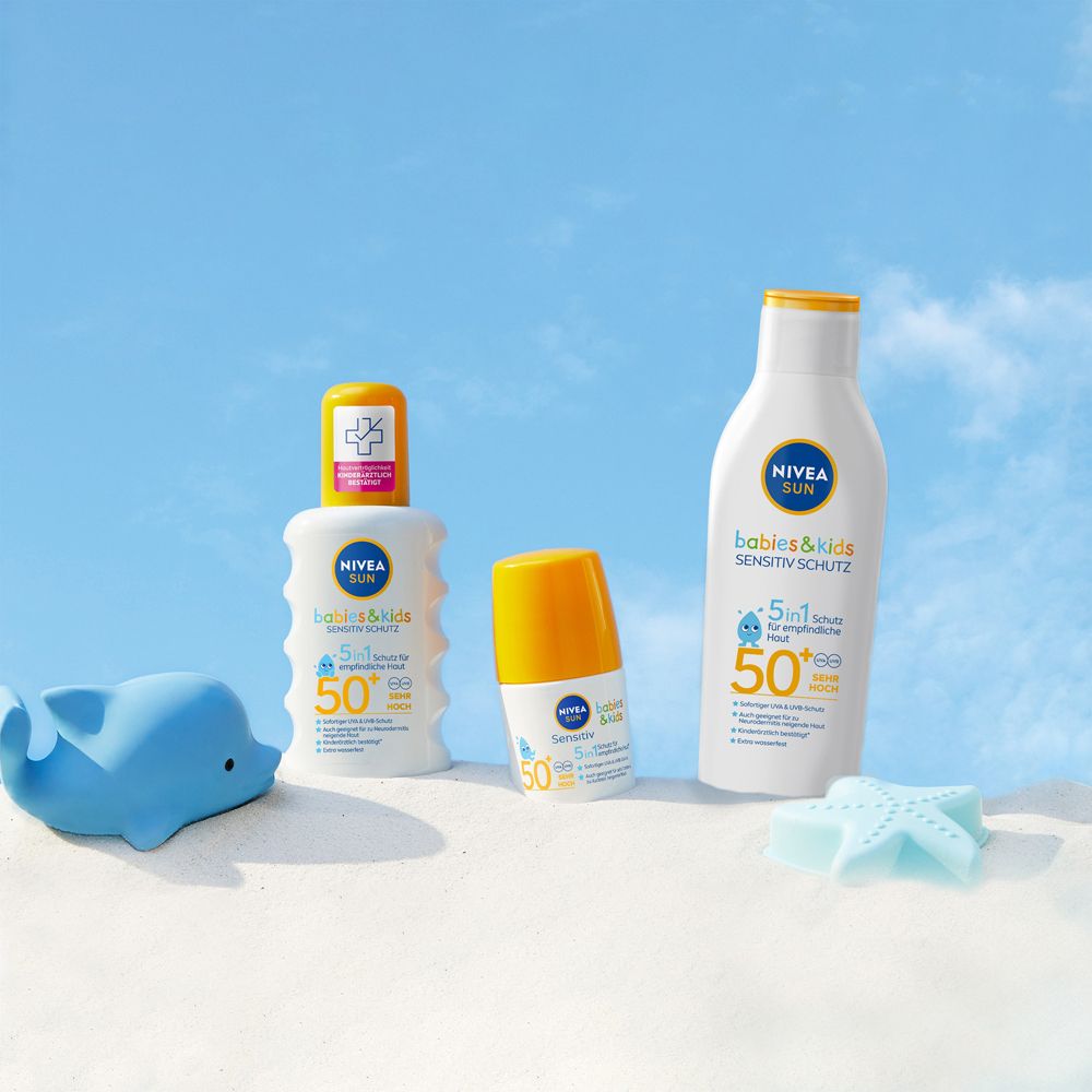Produits Nivea Sun Bébés & Enfants Protection Sensible SPF 50+ sur la plage avec des jouets.