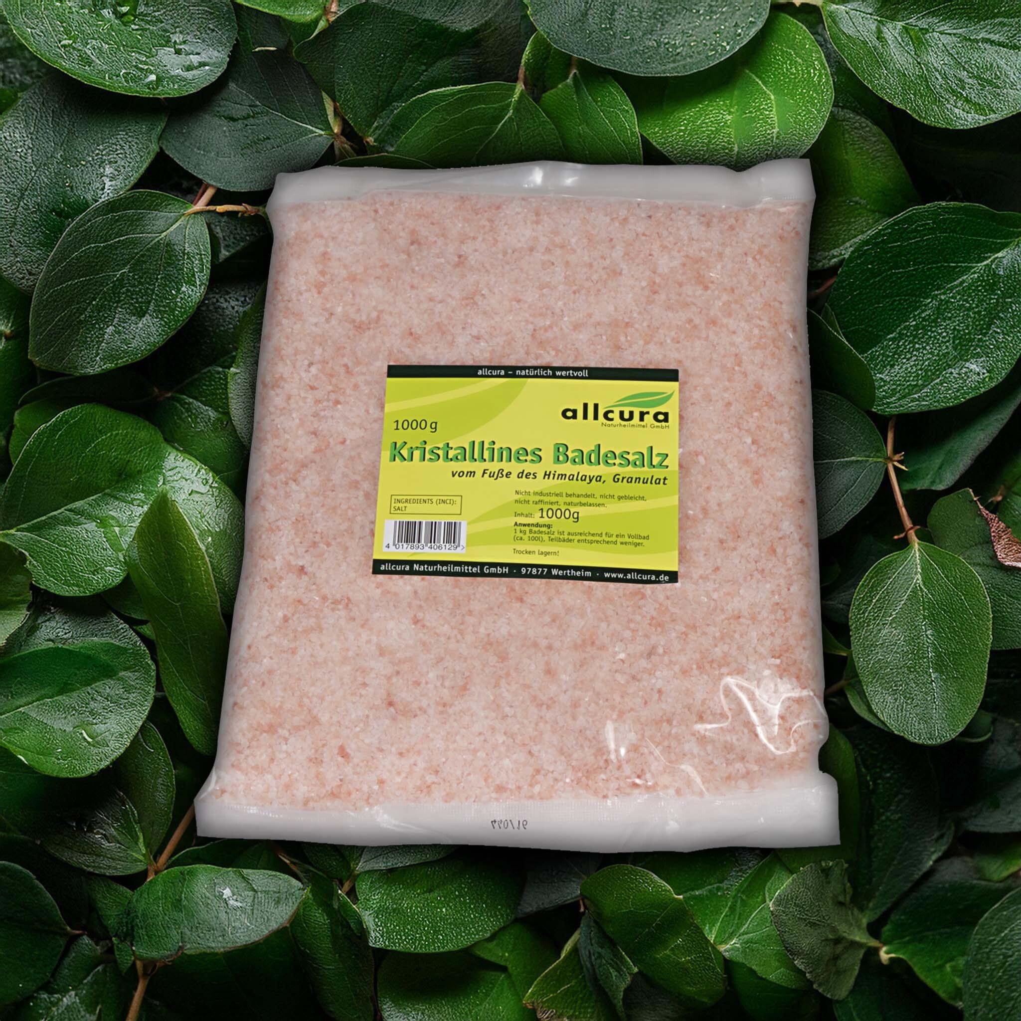 Emballage du produit avec sel de bain rose, entouré de feuilles vertes. L'étiquette affiche les informations sur le produit.