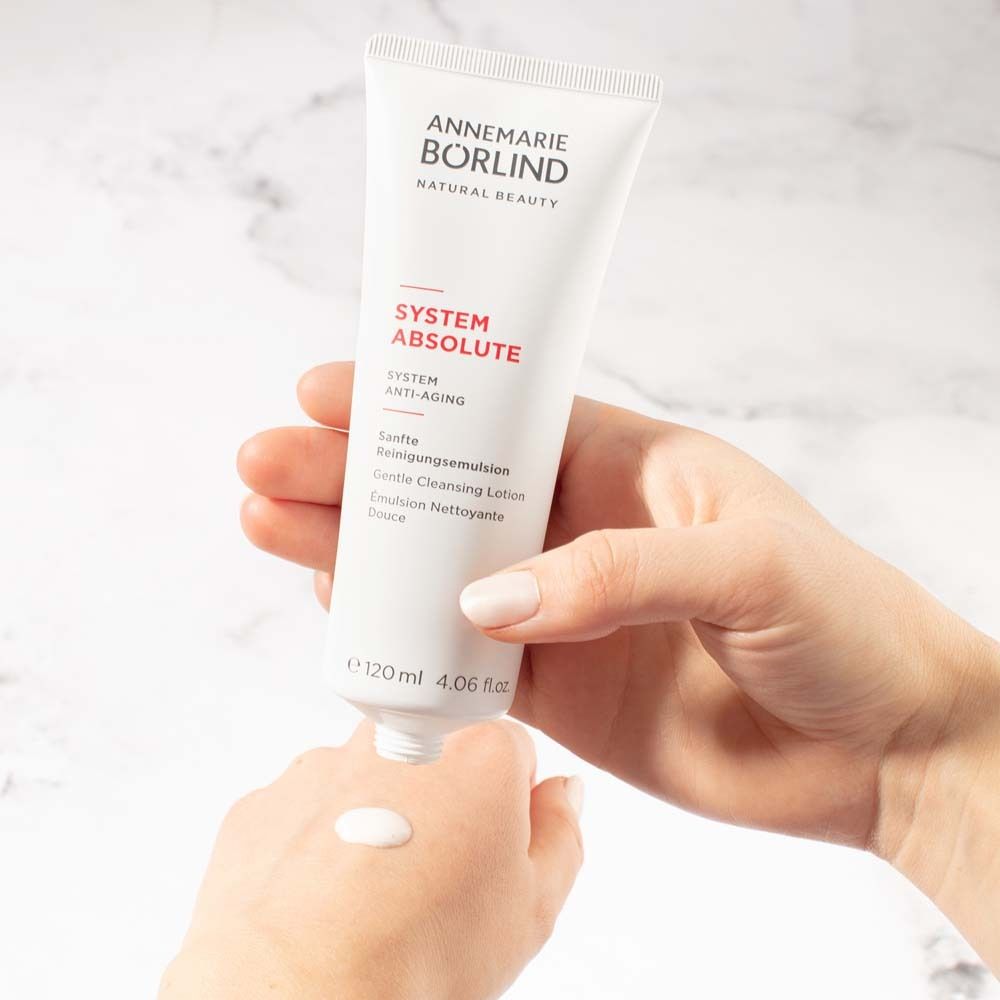 Tube blanc avec produit. Le produit est appliqué sur la main. Fermeture dorée.