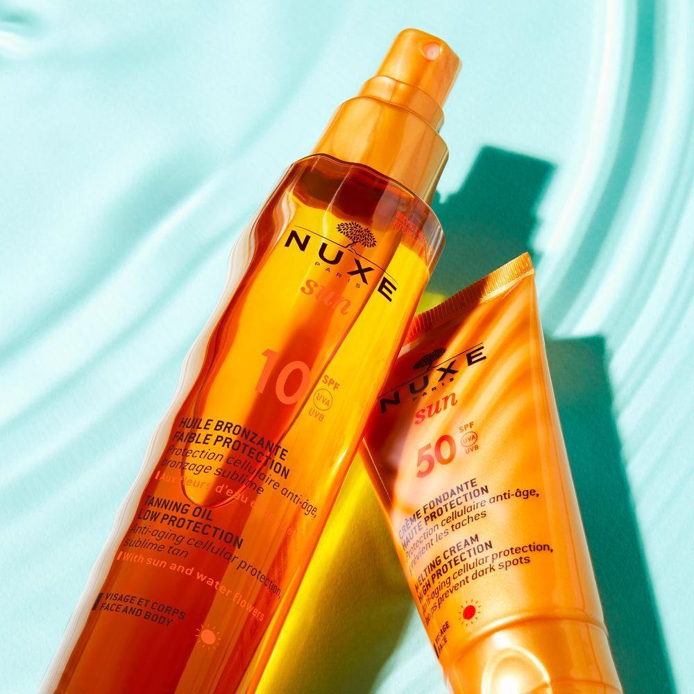 Huile solaire NUXE Sun SPF 10 et crème solaire SPF 50. Texte: Huile Bronzante, Crème Fondante. Sur fond bleu.