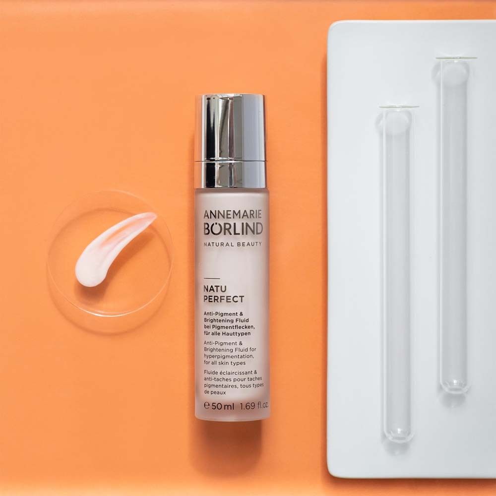 ANNEMARIE BÖRLIND NATU PERFECT avec accessoires. Fluide rose, plaque de verre, 2 tubes. Fond orange.