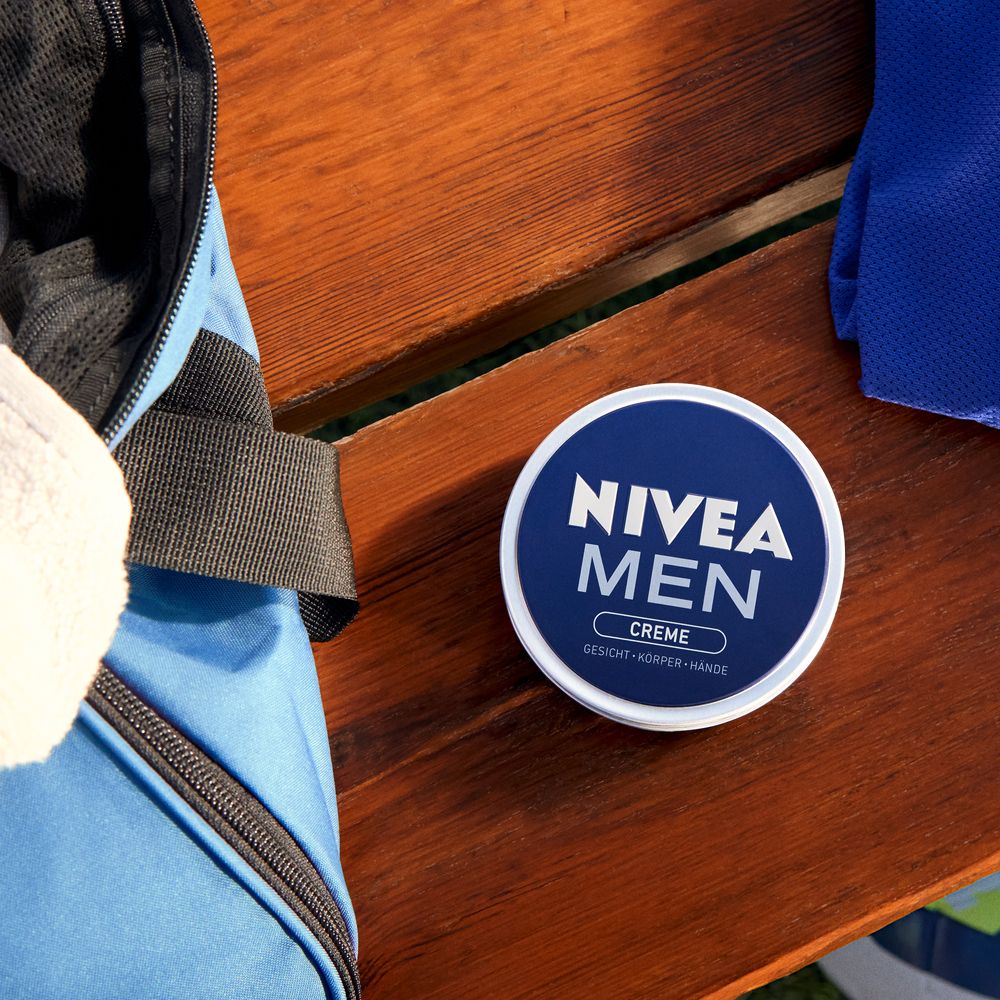 Boîte NIVEA MEN Crème sur une surface en bois à côté d'un sac de sport.