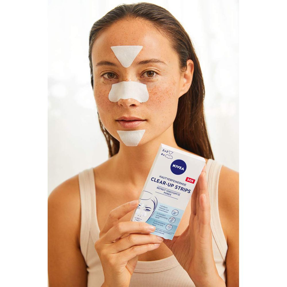 Femme avec des Bandes Purifiantes NIVEA sur le nez, le front et le menton. Elle tient l'emballage du produit.