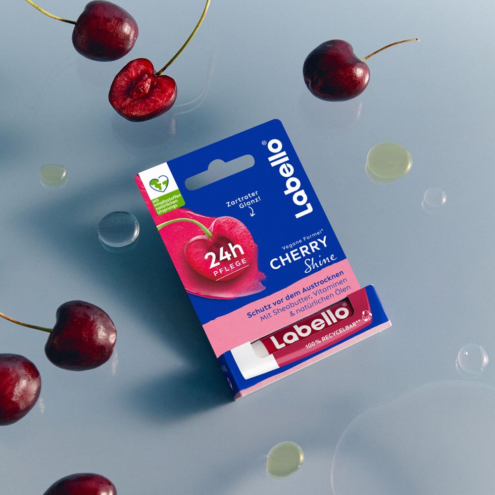 Labello Cherry Shine Lippenpflege verpackt mit Kirschen und Wassertropfen.