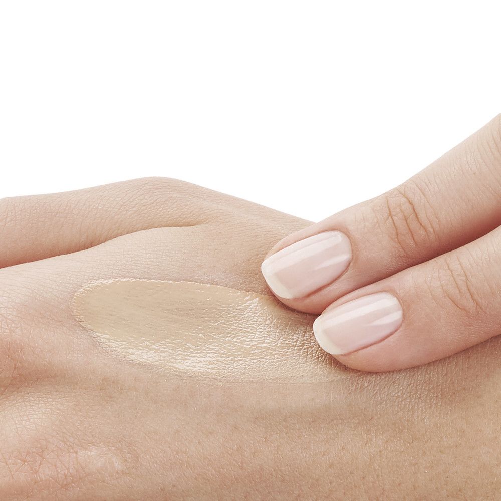 Main avec crème solaire appliquée. Teinte: beige clair.