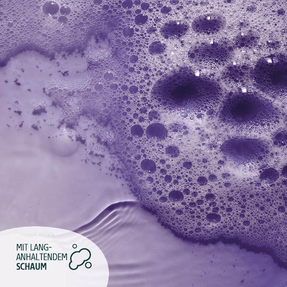 Gros plan sur bain moussant violet. Texte : Avec mousse longue durée. Bulles dans l'eau.