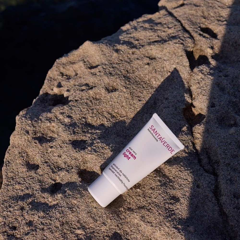Tube "cream light" blanc sur pierre. Logo SANTAVERDE visible. Produit de soin du visage. Perspective oblique.