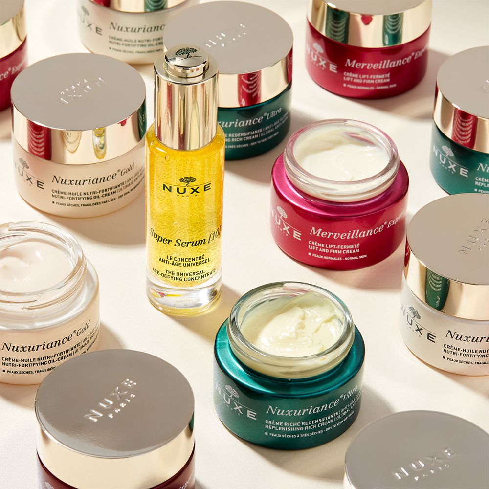 Verschiedene NUXE-Produkte: Cremes und Serum. Rosa, goldfarbene und grüne Verpackungen.