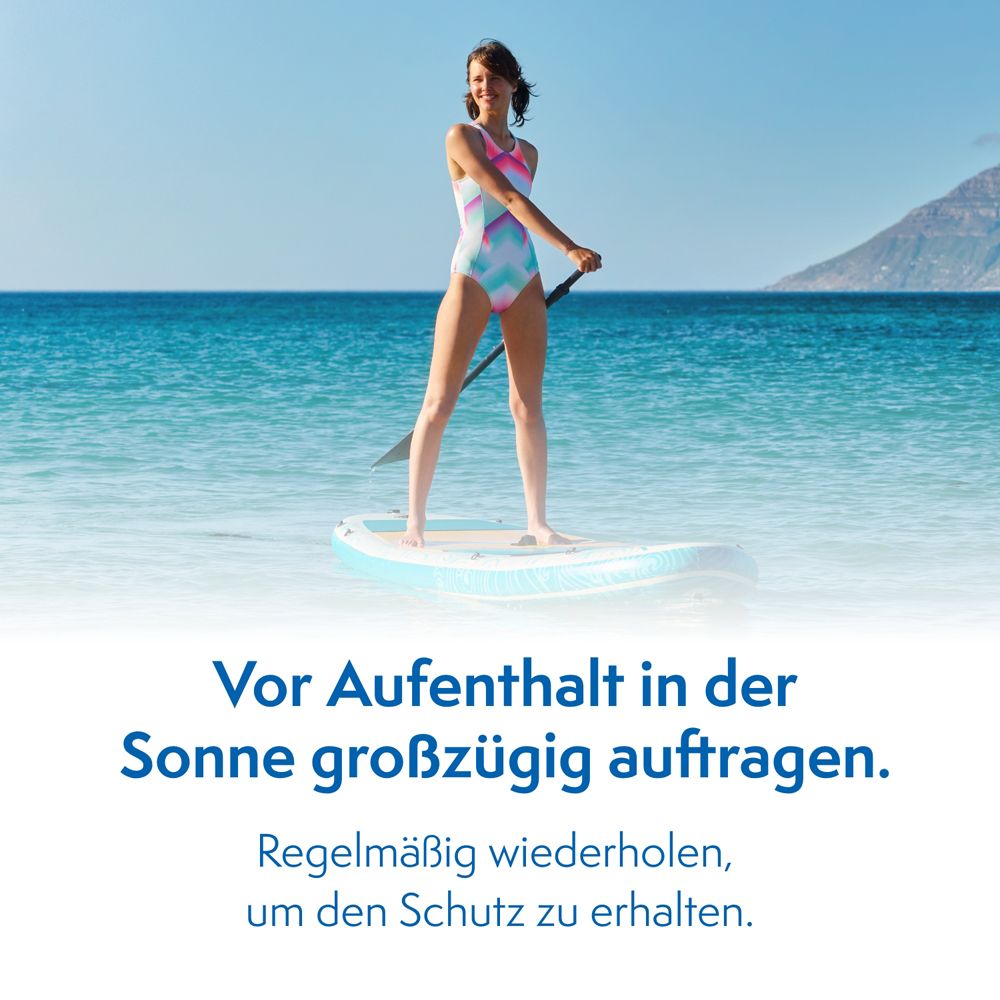 Femme sur une planche de surf dans la mer. Texte: Appliquer généreusement avant l'exposition au soleil. Répéter régulièrement.