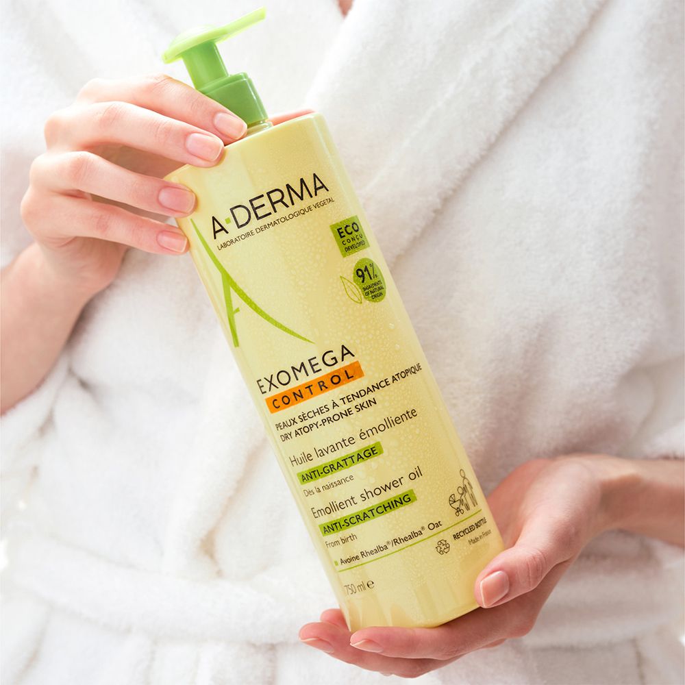 A-DERMA EXOMEGA CONTROL huile de douche. Flacon jaune avec pompe verte. Mains tenant le flacon. Texte: EXOMEGA CONTROL.