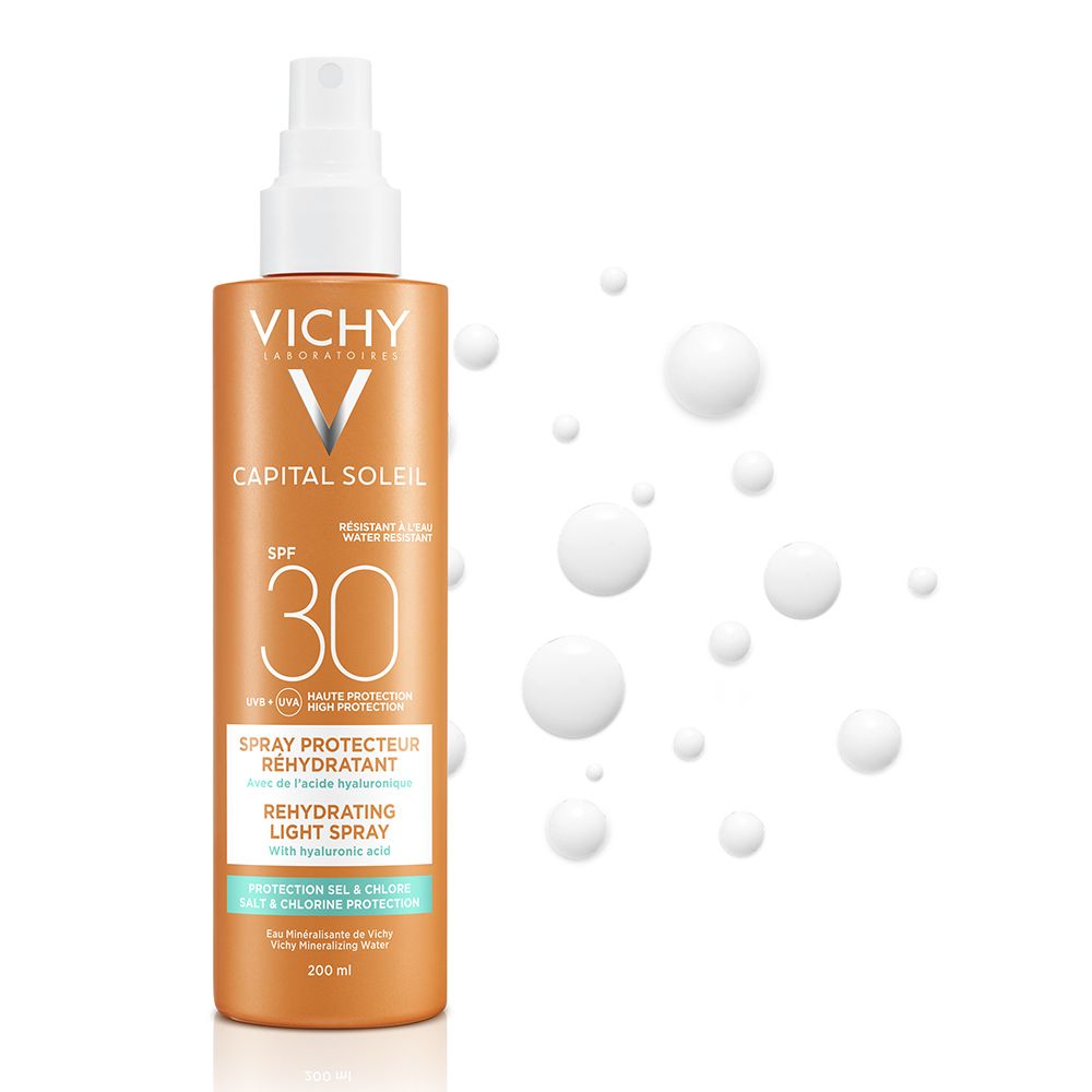 Spray solaire avec tête blanche. Inscriptions: VICHY, CAPITAL SOLEIL, SPF 30. Texte: Spray Protecteur Réhydratant. Gouttes blanches en arrière-plan.