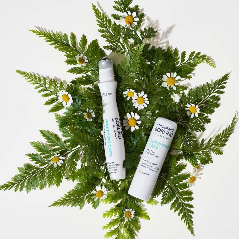 Deux roll-ons et un tube sur feuilles et fleurs. Texte: PURIFYING CARE. Marque: ANNEMARIE BÖRLIND.