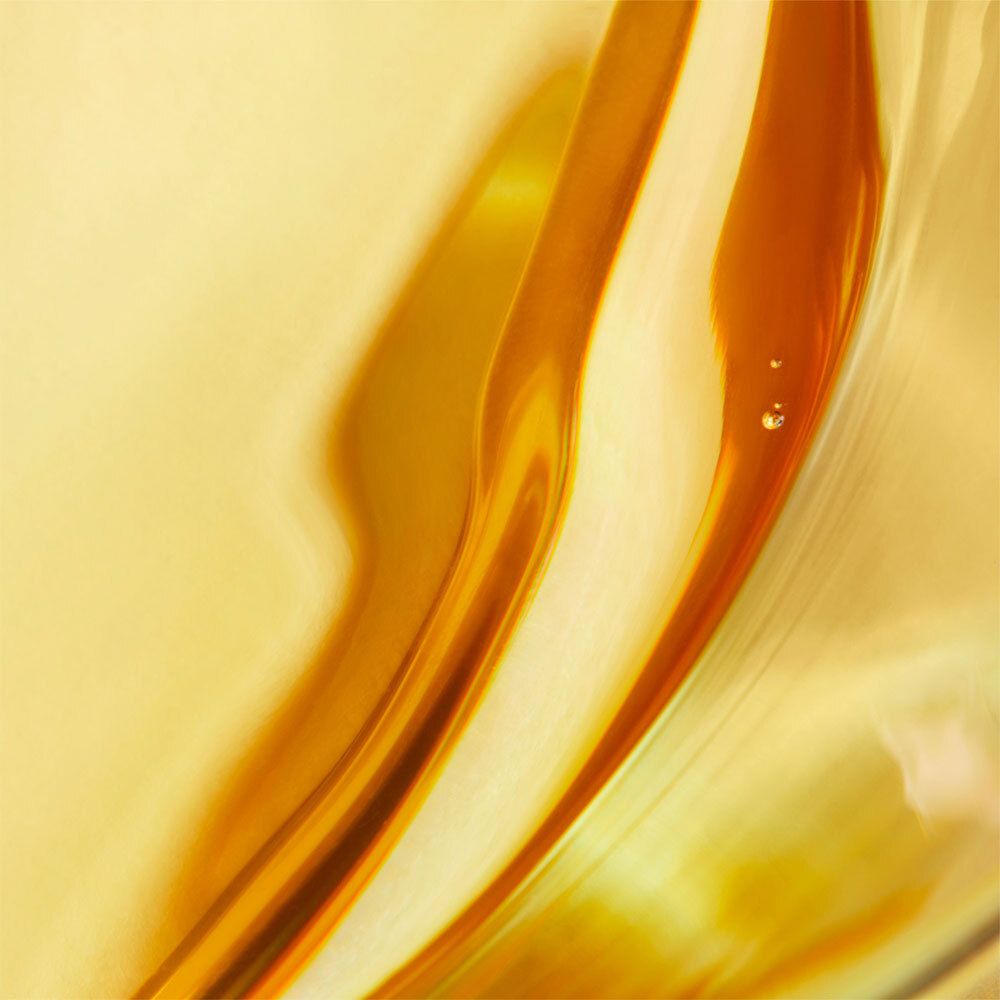 Gros plan abstrait de liquides dorés avec reflets. Deux gouttes sont visibles.