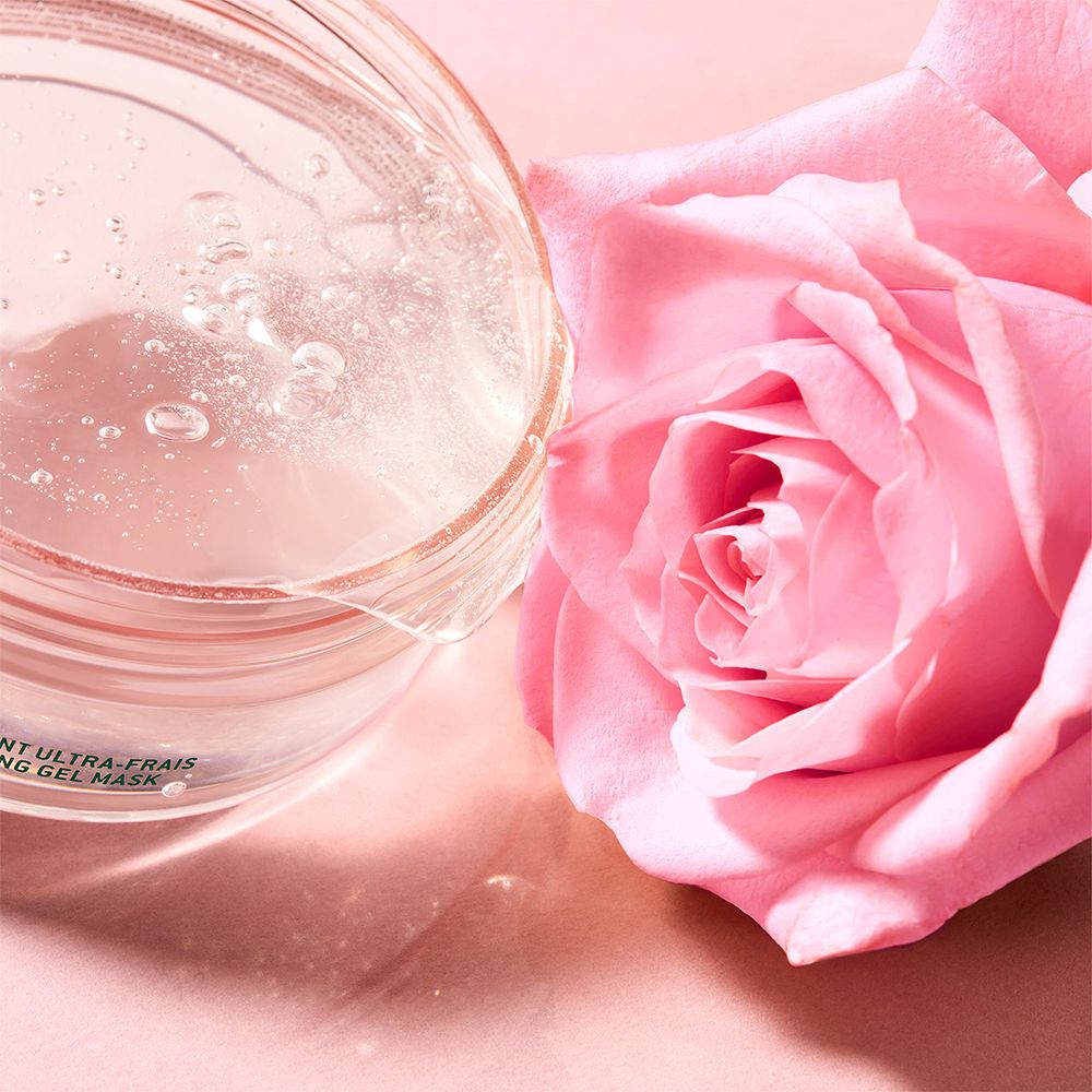 Klarer Gel-Maskenbehälter mit einer rosa Rose daneben.