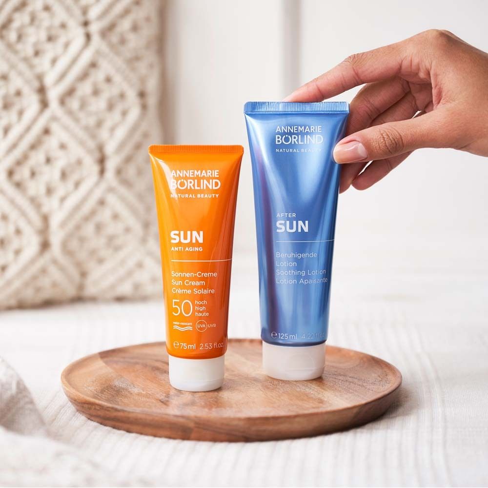 Deux tubes de crème solaire sur plateau en bois. Orange et bleu. Texte: ANNEMARIE BÖRLIND SUN.
