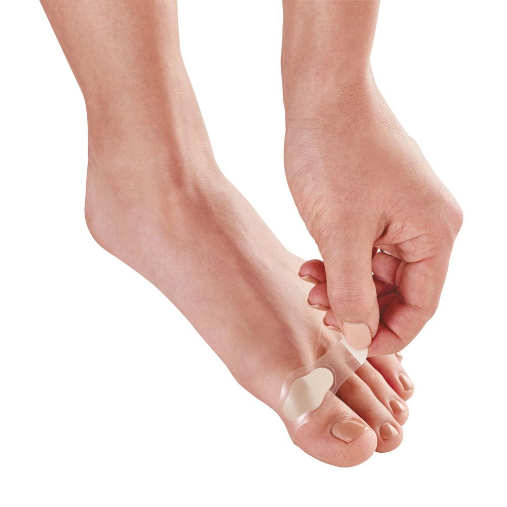 Personne appliquant un pansement ampoule entre les orteils. Gros plan sur les pieds.