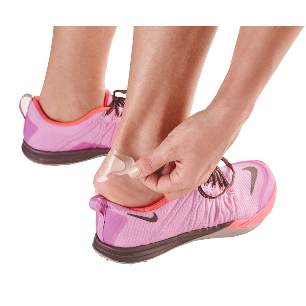 Personne appliquant un pansement ampoule sur le talon. Chaussures de sport roses.