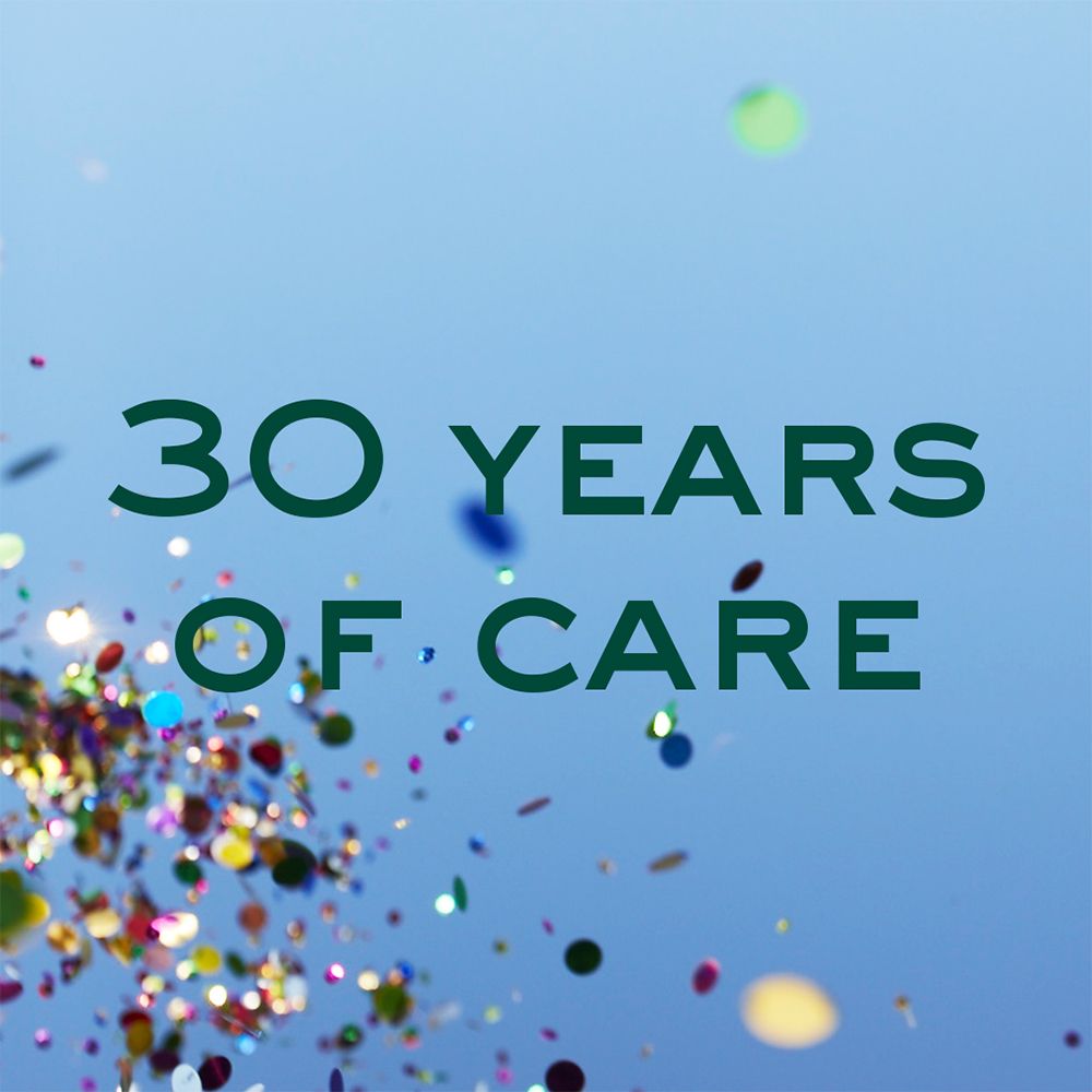 Texte: 30 YEARS OF CARE. Texte vert sur fond bleu avec confettis.