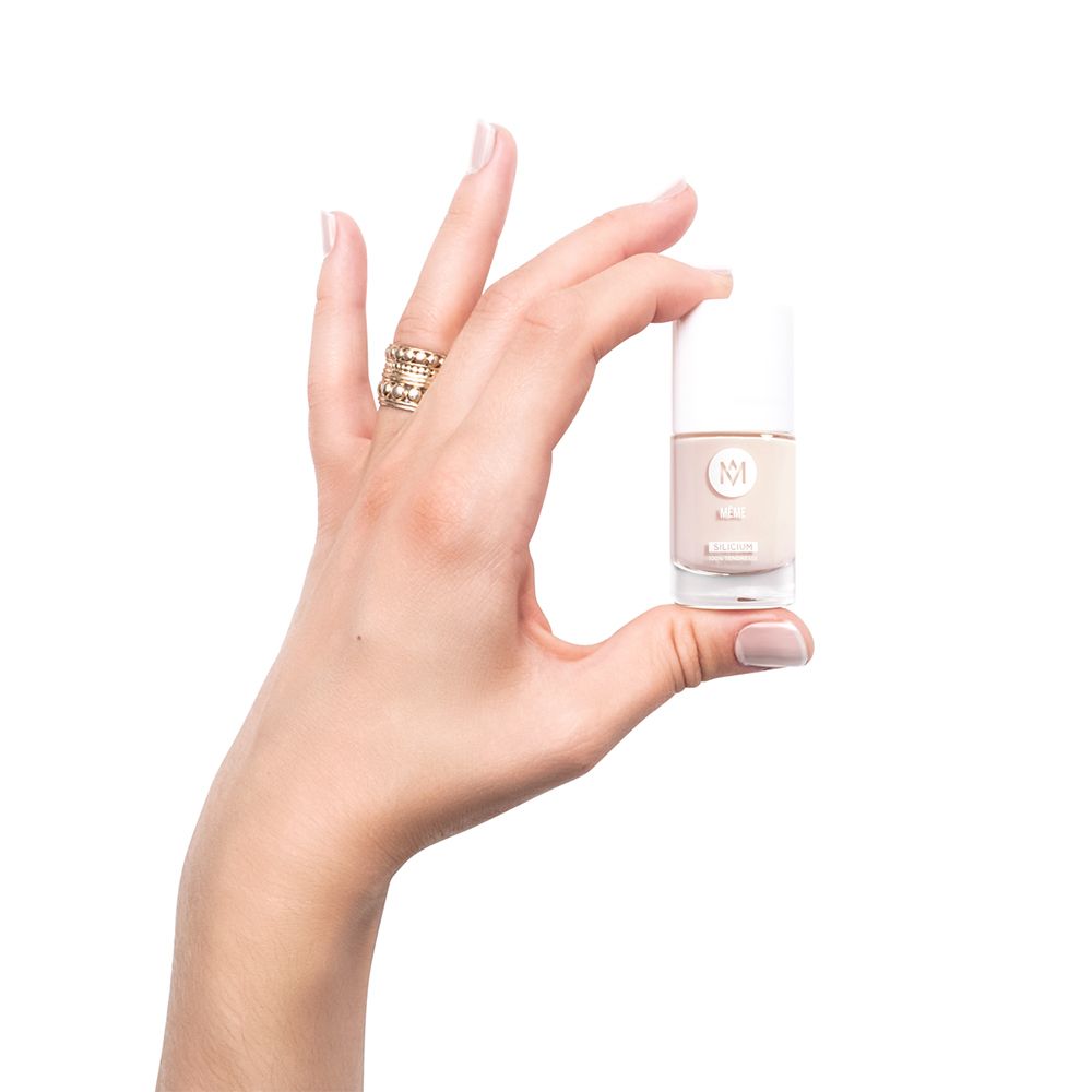 Hand hält ein kleines Nagellackfläschchen. Rosa Nagellack. Weißer Deckel. Aufschrift: MÊME.