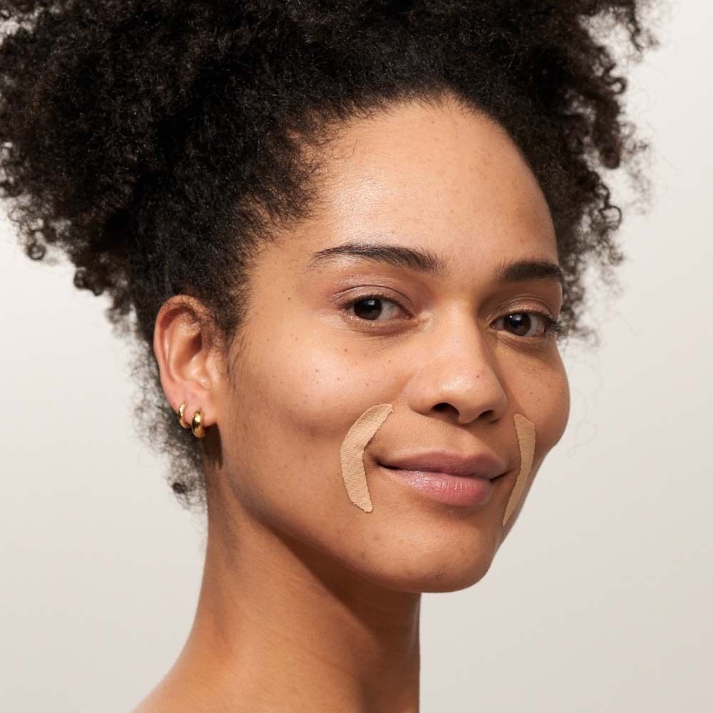 Frau mit Patches auf der Haut. Beige Patches an den Mundwinkeln. Natürlicher Hintergrund.