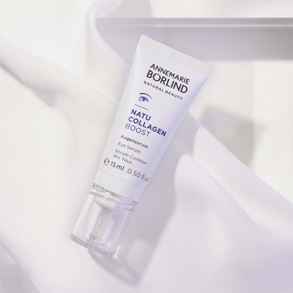 Tube blanc avec texte violet. Contient un sérum pour les yeux. Marque : ANNEMARIE BÖRLIND. Sur tissu blanc.