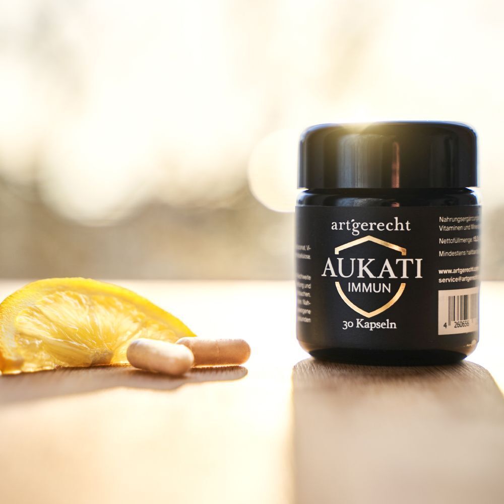 Schwarze Dose mit Aufschrift AUKATI IMMUN, 30 Kapseln. Zitrone und Kapseln daneben.
