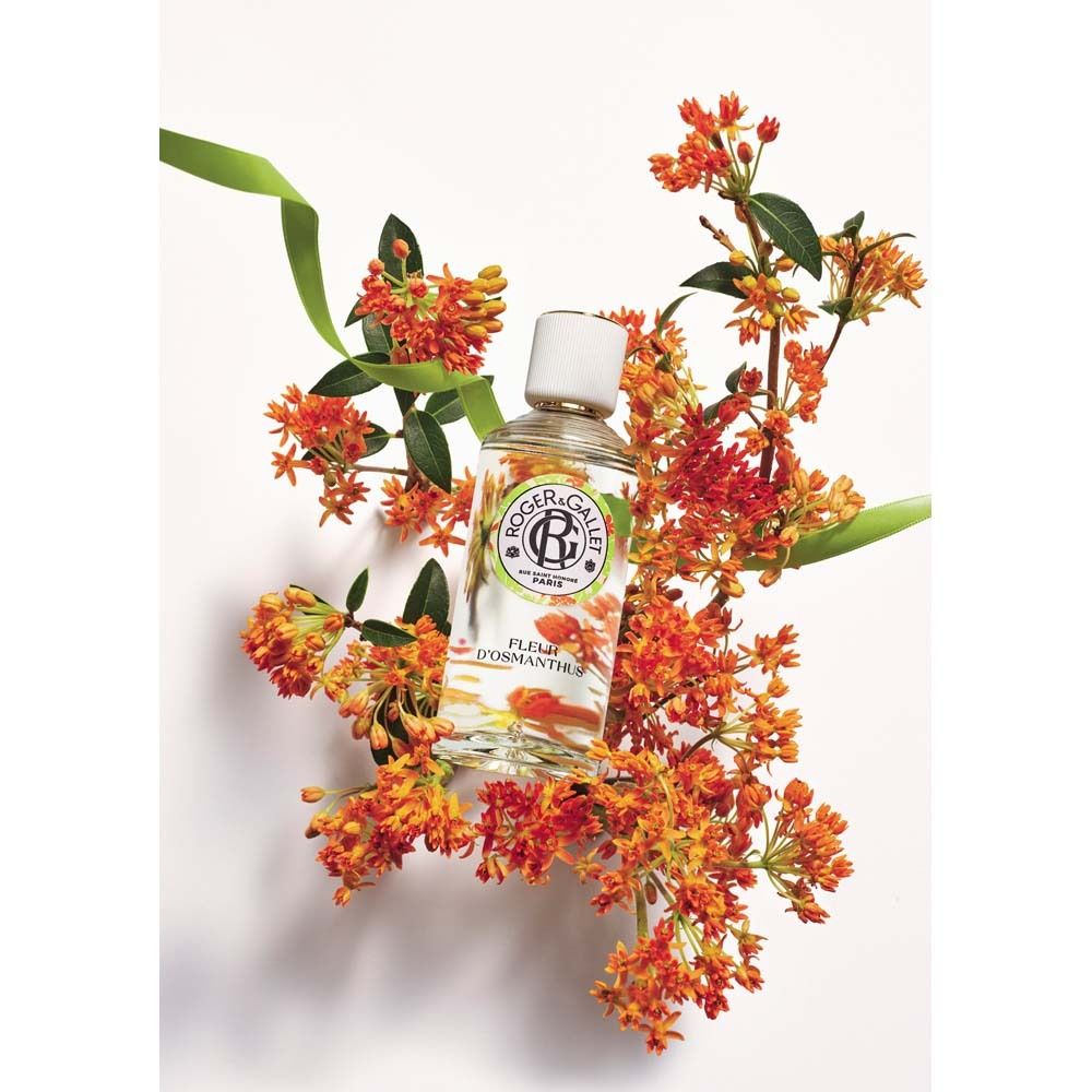 Flacon en verre avec bouchon blanc, entouré de fleurs oranges. Nom du produit: Fleur d'Osmanthus.