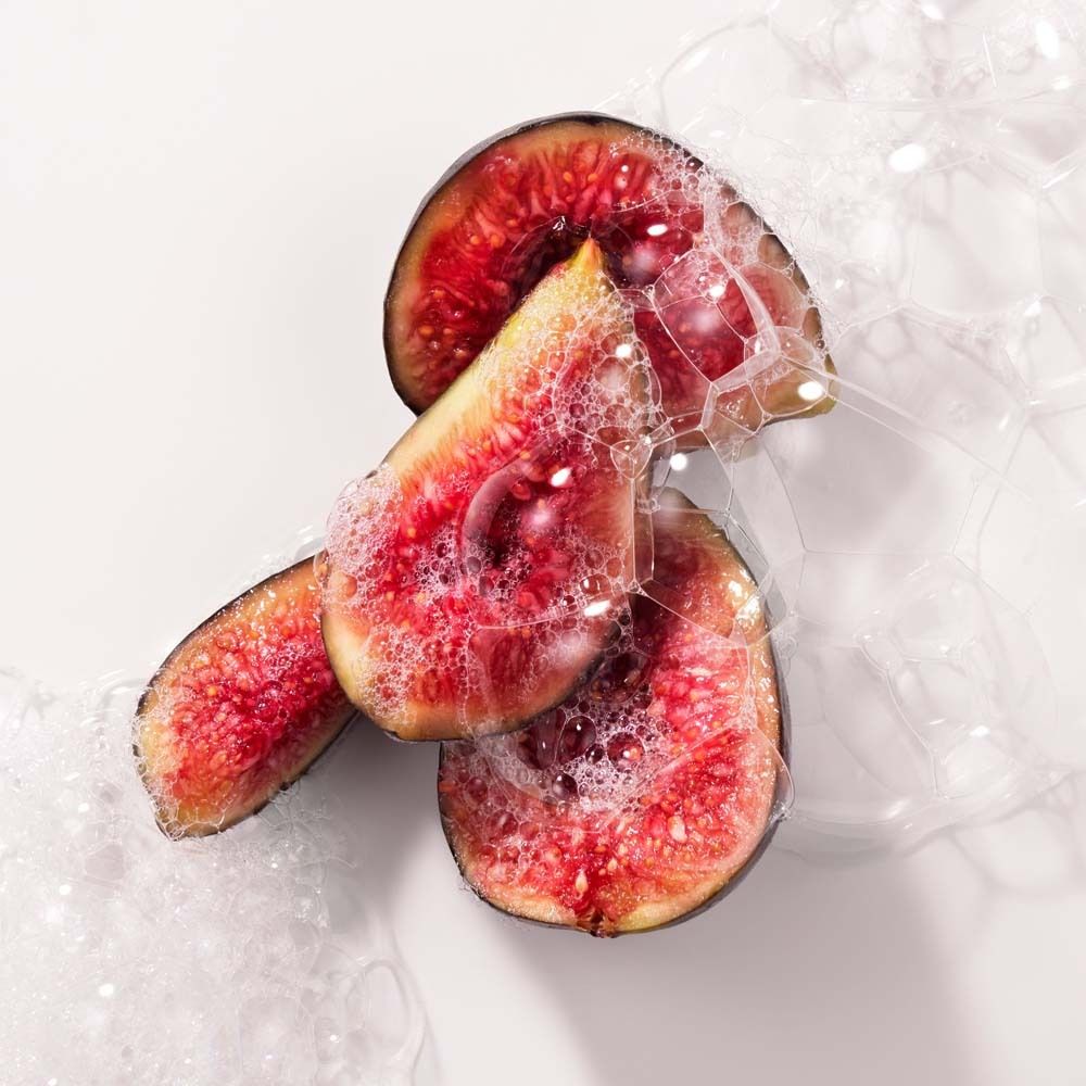 Figues coupées dans des bulles de savon. Chair rouge, peau foncée. Fond blanc. Gros plan.