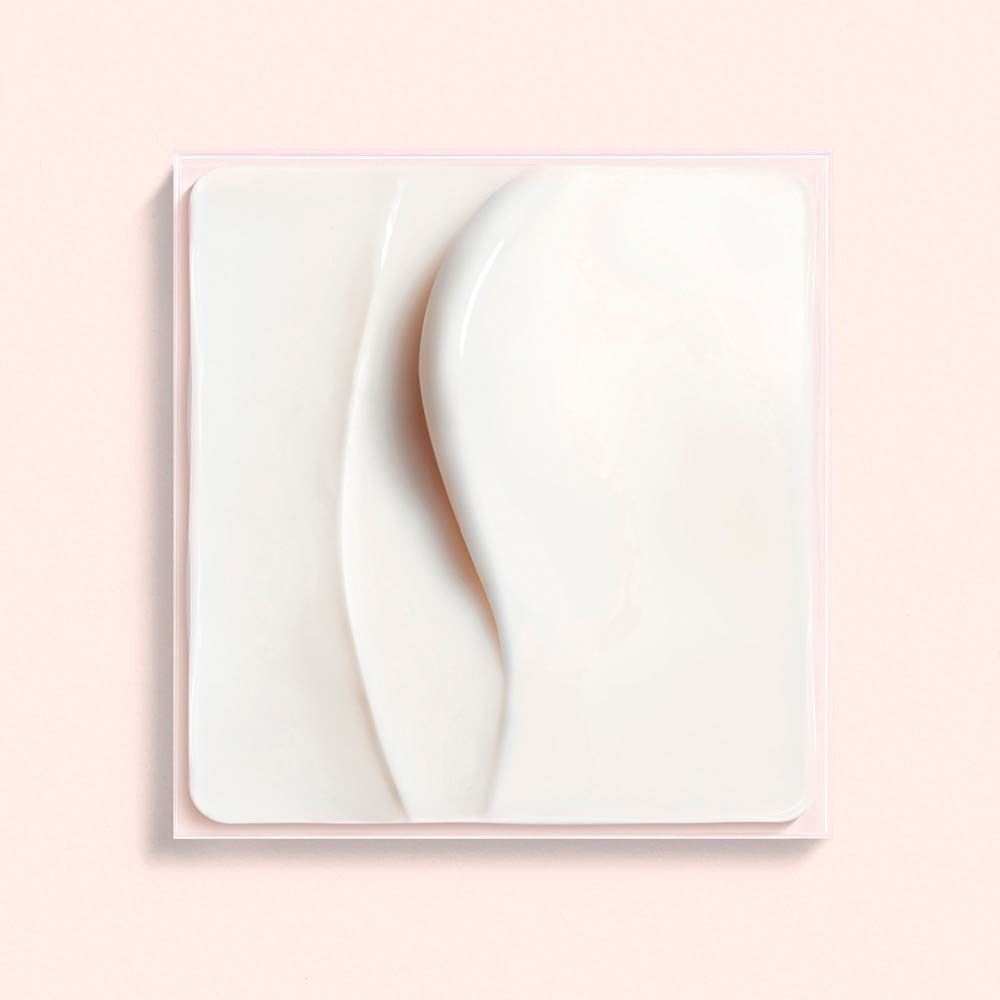 Quadratische, weiße Creme-Textur auf rosa Hintergrund. Glatte Oberfläche mit wellenförmigen Spuren.