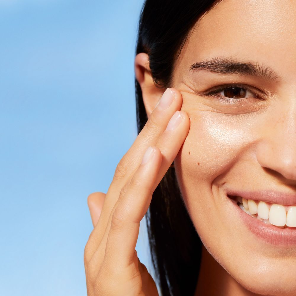 Femme touchant son visage. Peau brillante. Fond bleu.
