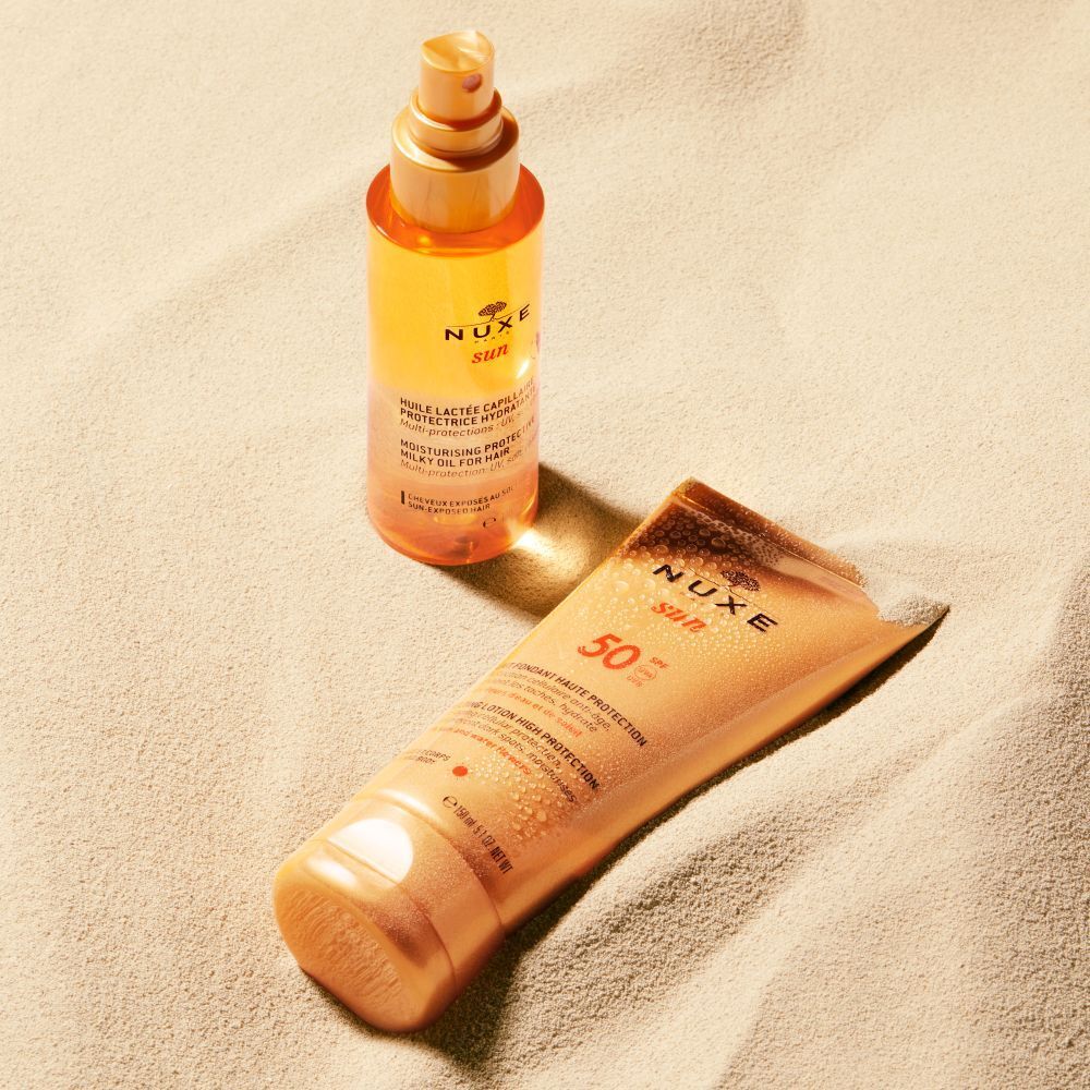 Deux produits NUXE Sun sur du sable. Lait solaire et huile.
