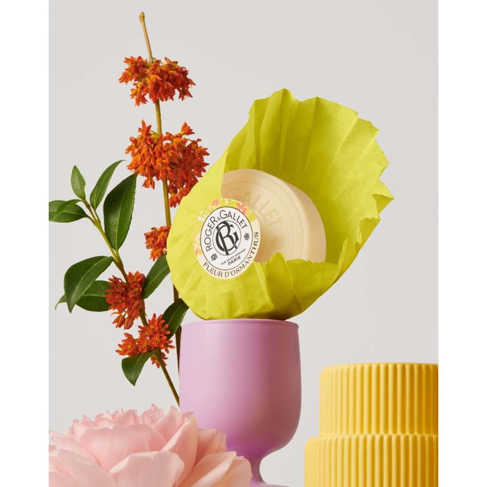 Savon en papier jaune, à côté de fleurs et d'une tasse rose. ROGER&GALLET, Fleur d'Osmanthus.
