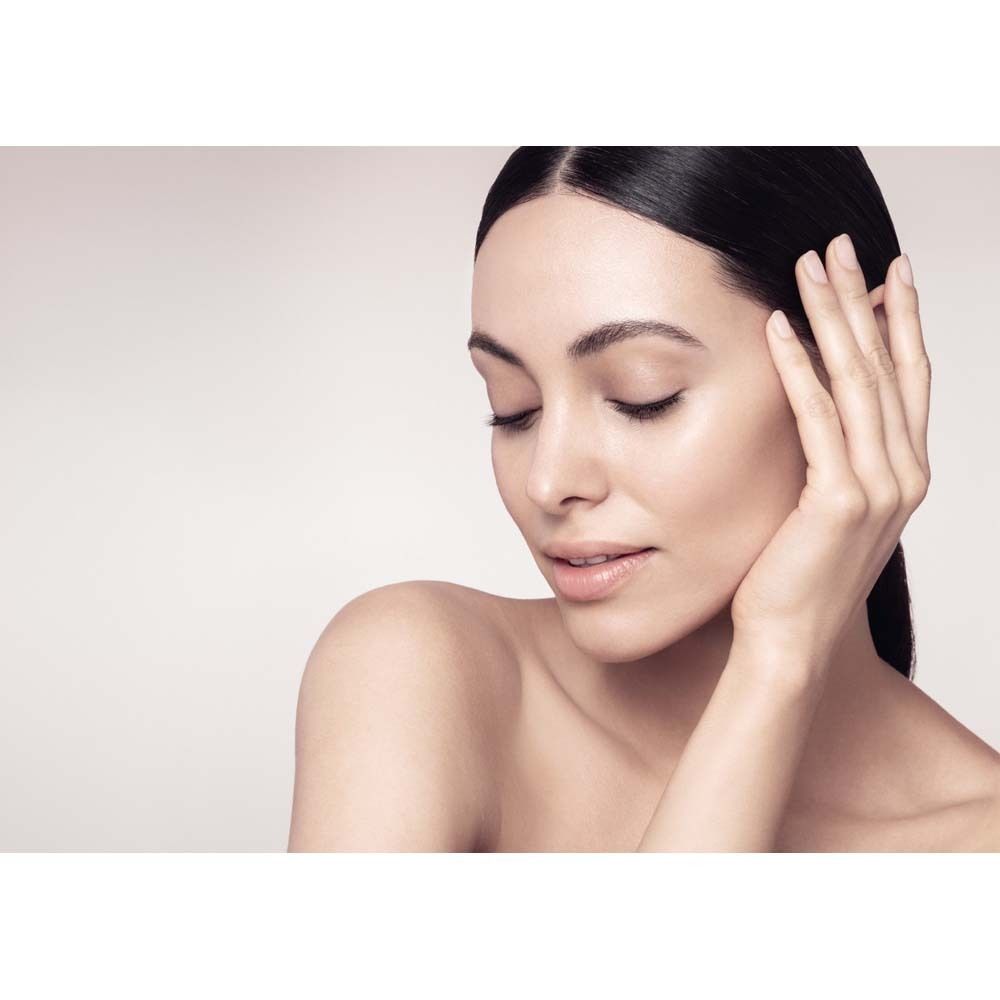 Gros plan d'une femme aux yeux fermés, posant doucement sa main sur sa joue. Peau claire, cheveux foncés.