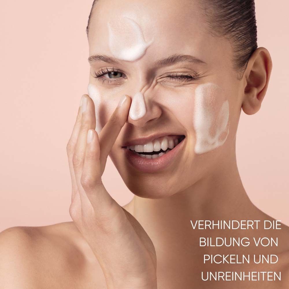Frau mit Schaum im Gesicht. Text: Verhindert die Bildung von Pickeln und Unreinheiten.