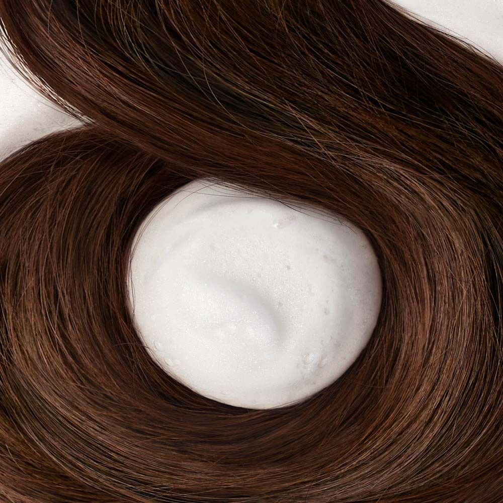 Gros plan sur des cheveux bruns avec une boule de mousse blanche au centre.