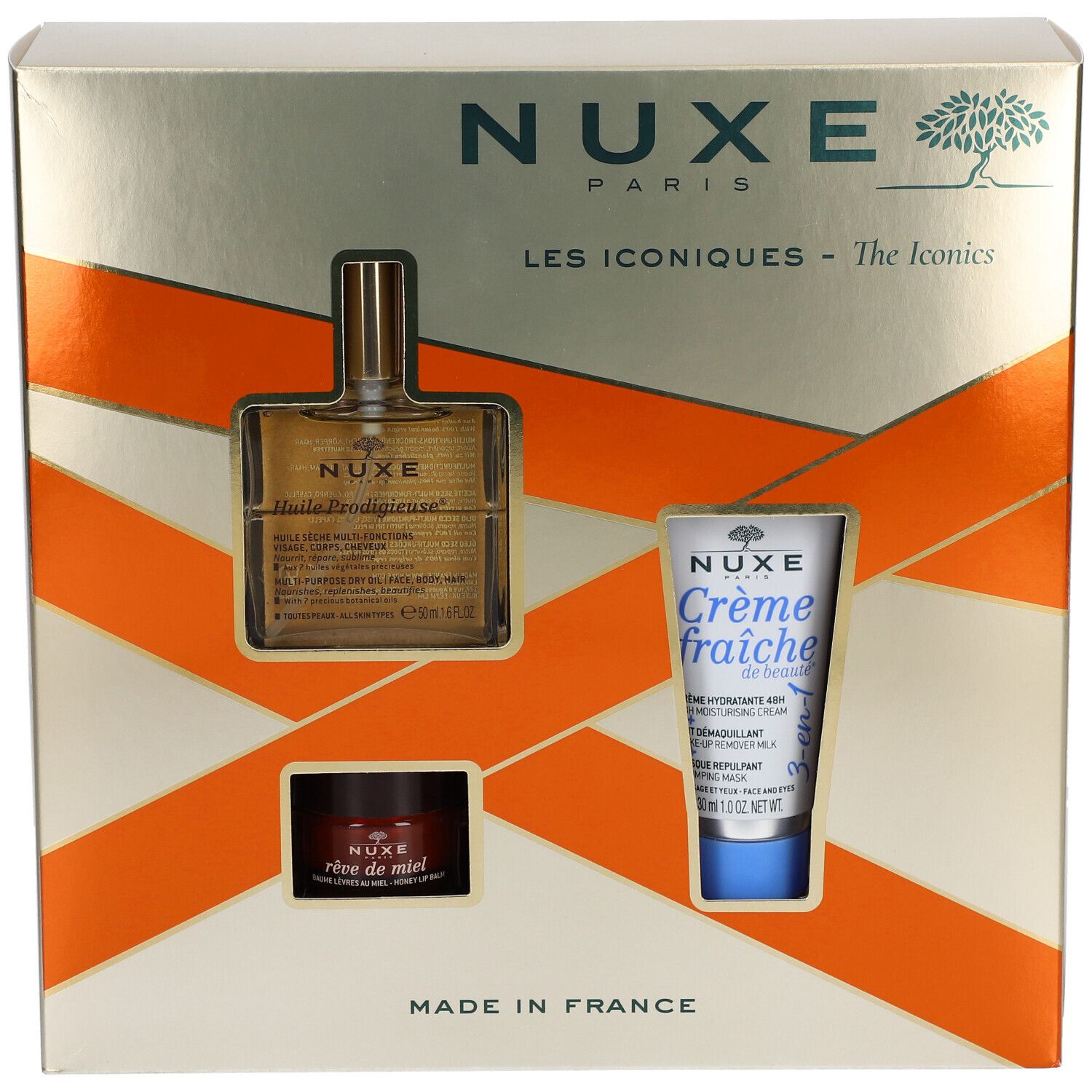 Geschenkbox mit drei NUXE-Produkten. Sichtbar: Öl, Creme und Balsam. Goldene Verpackung mit orangefarbenen Akzenten. "Made in France".