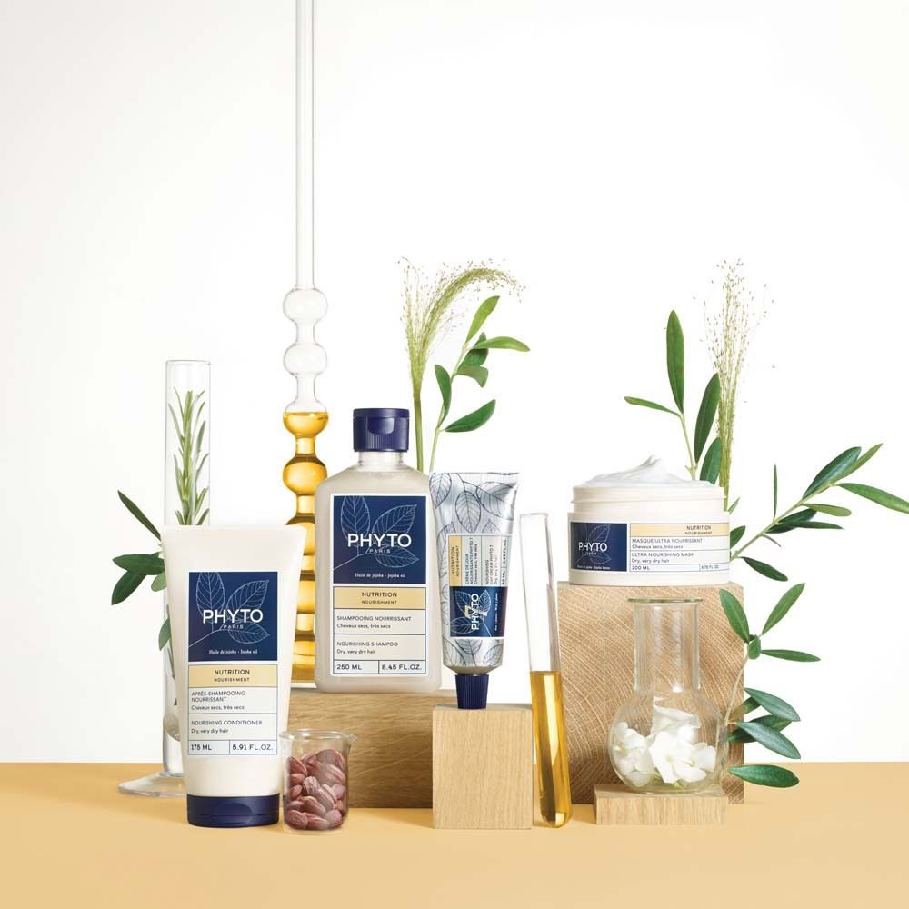 Produktpräsentation mit verschiedenen PHYTO PARIS Produkten. Flaschen, Tiegel und Tuben, umgeben von Pflanzen und Laborutensilien.