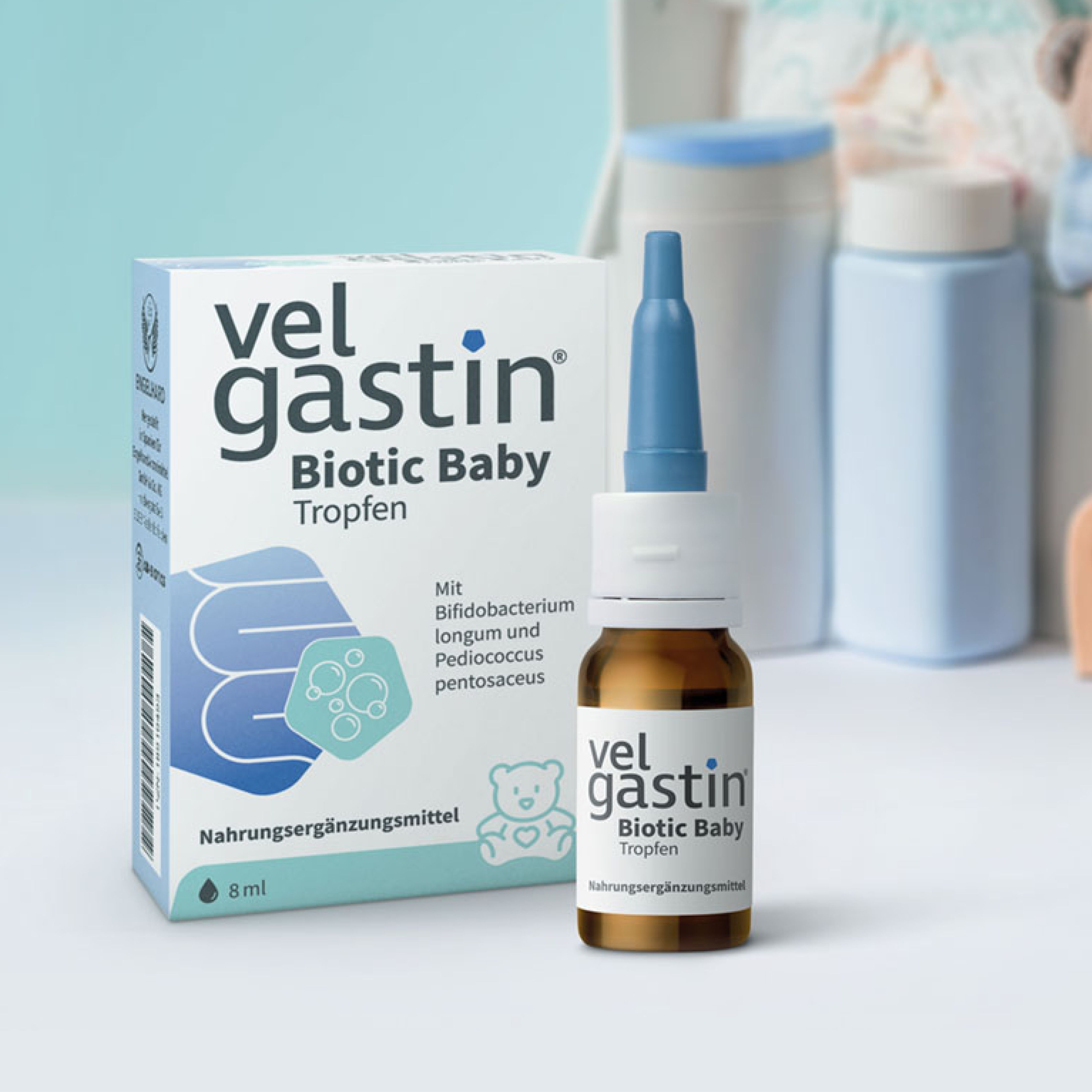 Tropfenflasche und Verpackung. Aufschrift: Velgastin Biotic Baby Tropfen. Hintergrund: Babyartikel.