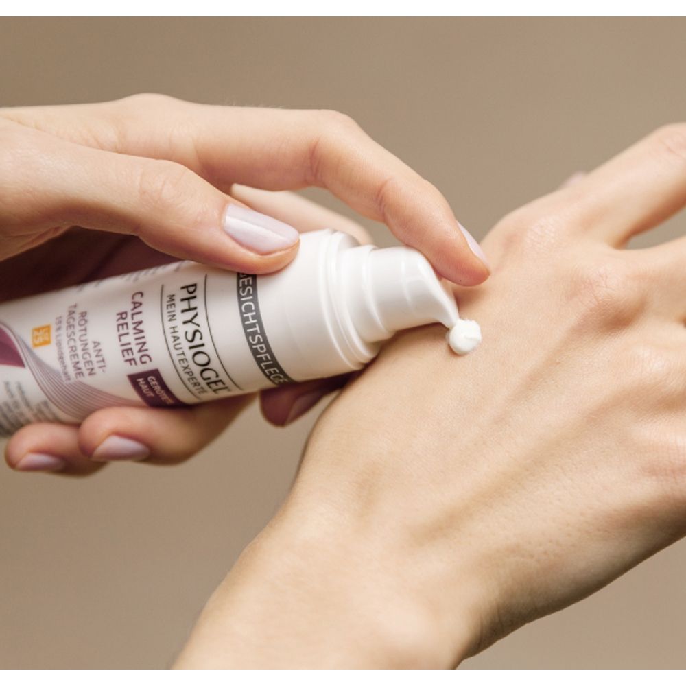 Hand drückt Creme aus Tube. Tube: Physiogel Calming Relief Anti-Rötungen Tagescreme.